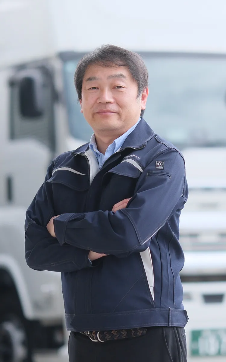 大型トラックを背に立つ代表取締役
