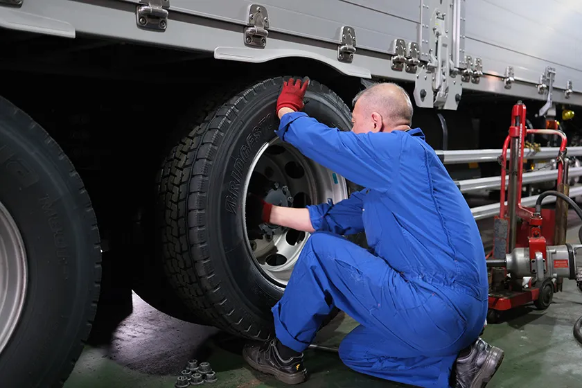 整備工場で大型車のタイヤを交換する整備スタッフ
