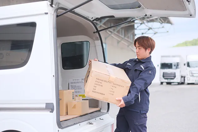 軽貨物車に荷物を積み込む配送スタッフ