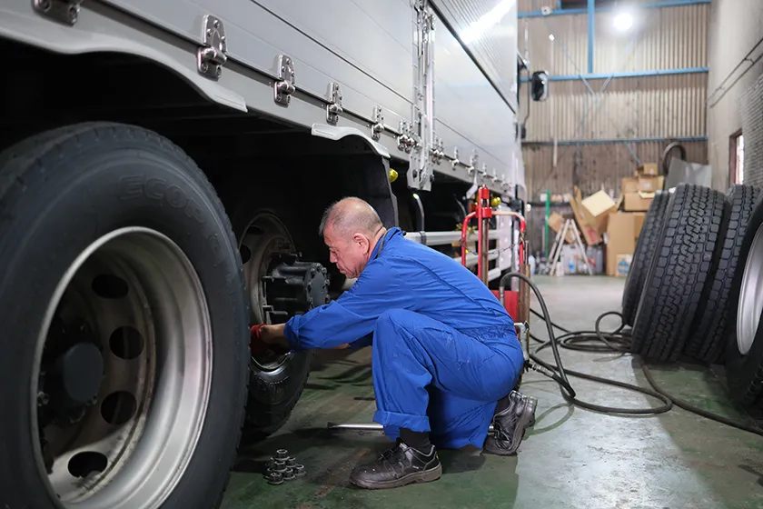 整備工場で大型車のタイヤを整備するスタッフ