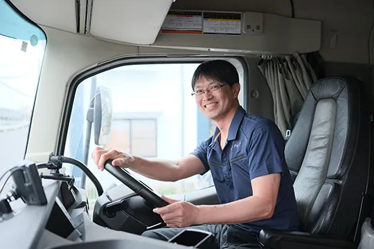 大型トラックの運転席で笑顔を見せるドライバー