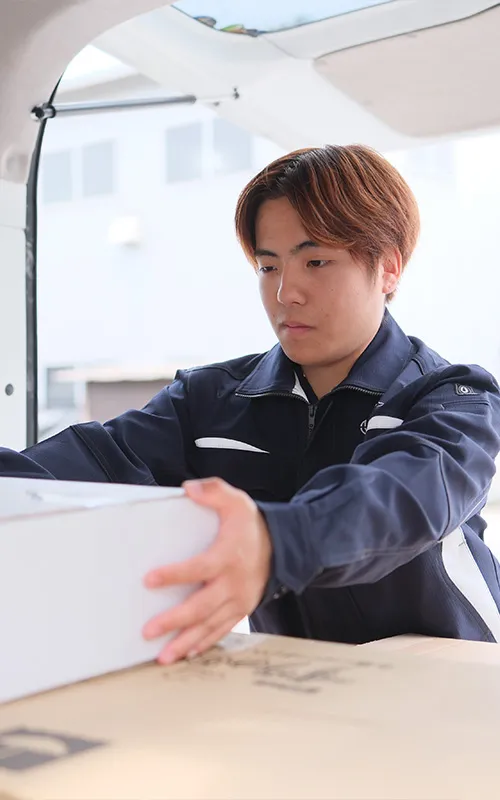 配送車で荷物を扱う若手スタッフ