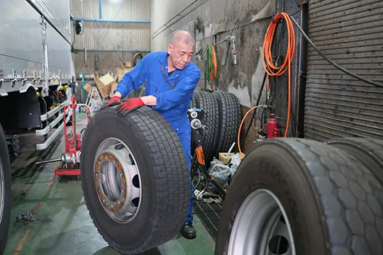 自社整備工場で大型車のタイヤを整備するスタッフ