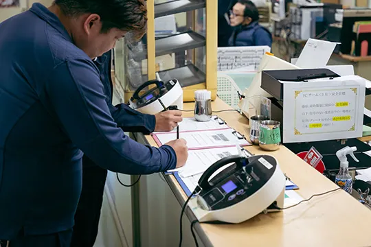 点呼記録を記入するスタッフとアルコール検知器