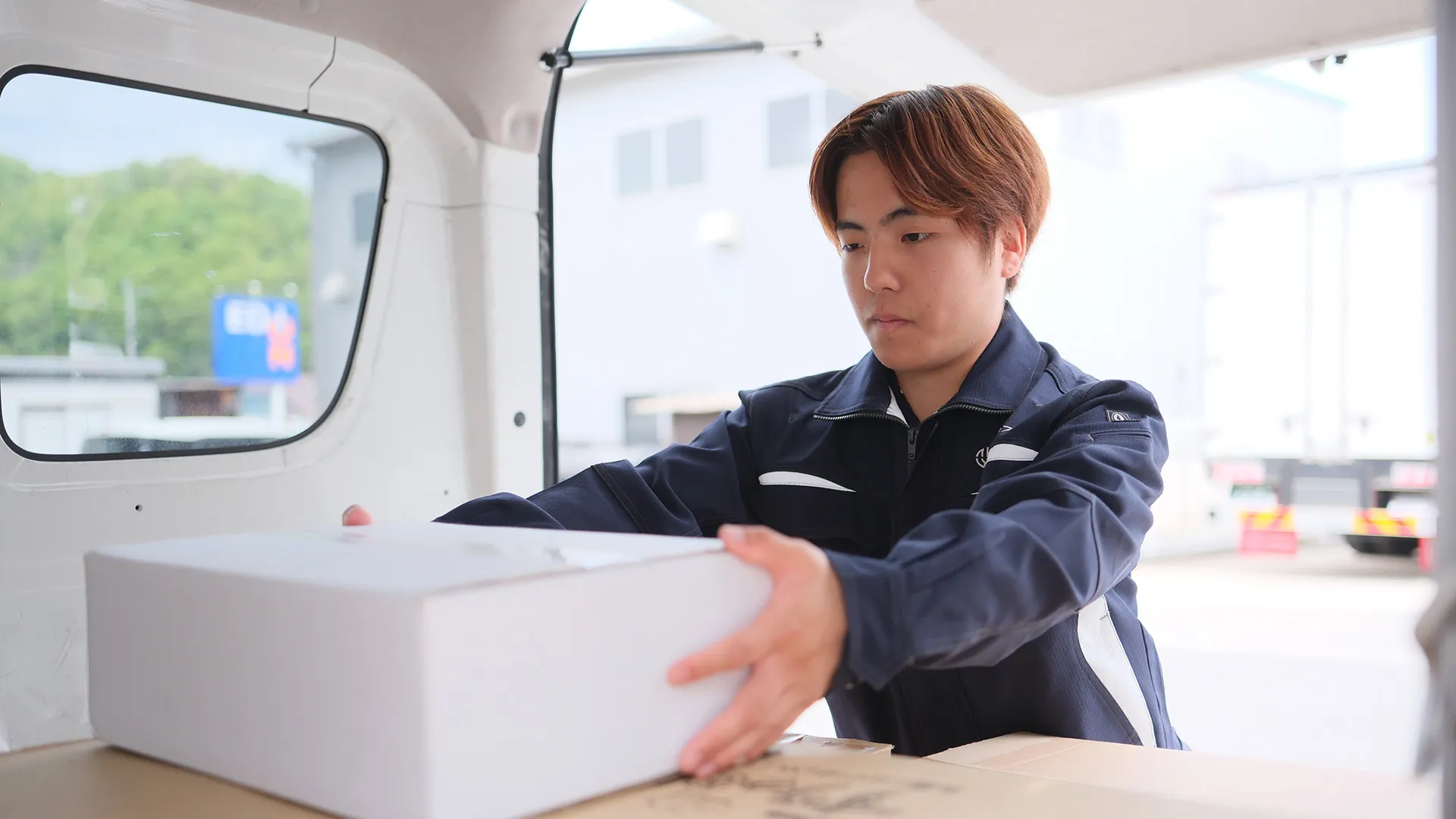 配送車に荷物を積み込む若手スタッフ